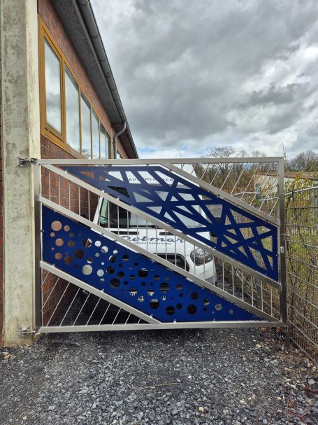 Bunte Metalltore mit geometrischem Design und sichtbarem Fahrzeug dahinter.